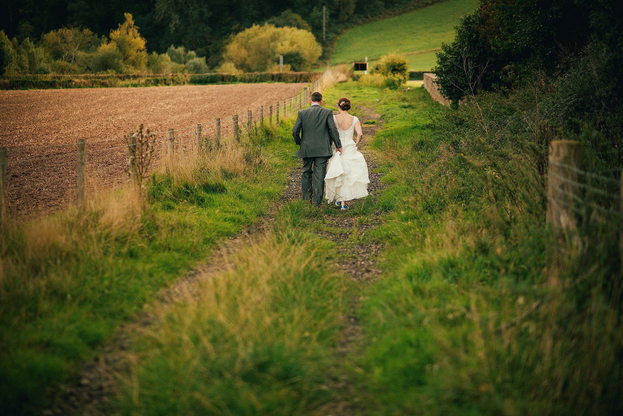 bride and groom in field during golden hour